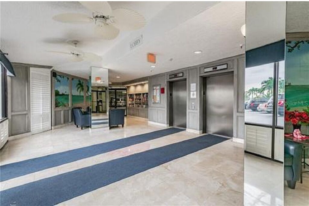 A hotel lobby with a reception desk, a seating area, and an elevator.