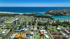 An aerial view of a coastal residential area with houses, roads, and a beach.