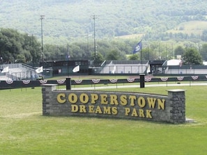 Segnale per Cooperstown Dreams Park, con base in pietra e campo erboso sullo sfondo.