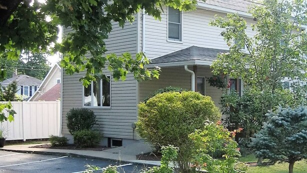 A two-story house with a front porch, a small front yard with a hedge, and a driveway. - Cooperstown Baseball Rentals - Columbia House (Oneonta)