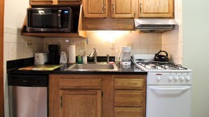 A kitchen with wooden cabinets, a microwave, a coffee maker, a toaster, a sink, and a stove.