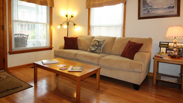 A living room with a beige sofa, a wooden coffee table, and a lamp on a side table.