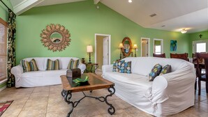 A living room with two white sofas, a wooden coffee table, and a green wall.