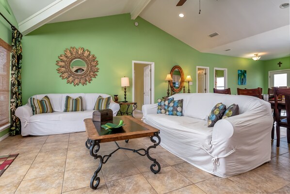 A living room with two white sofas, a wooden coffee table, and a green wall. - Gulf-side Beach house, great layout on beach and close walk to water! - Beach Br (Dauphin Island)