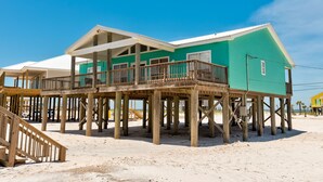 A beachfront house with a balcony, wooden deck, and multiple levels.