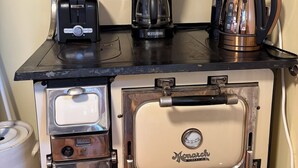 Una cocina con una estufa antigua, una cafetera, un tostador y un hervidor.