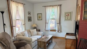 Una sala de estar con sofá, sillón, mesa de centro y mueble para televisión.