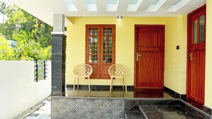 Una entrada moderna con una pared amarilla, dos puertas de madera y una pared de piedra.