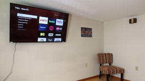 A living room with a flat-screen TV mounted on the wall displaying various streaming services. - Cooperstown Baseball Rentals - 1st Baseman (Oneonta)