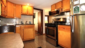 A kitchen with wooden cabinets, a stainless steel refrigerator, a stove, and a microwave. - Cooperstown Baseball Rentals - 1st Baseman (Oneonta)