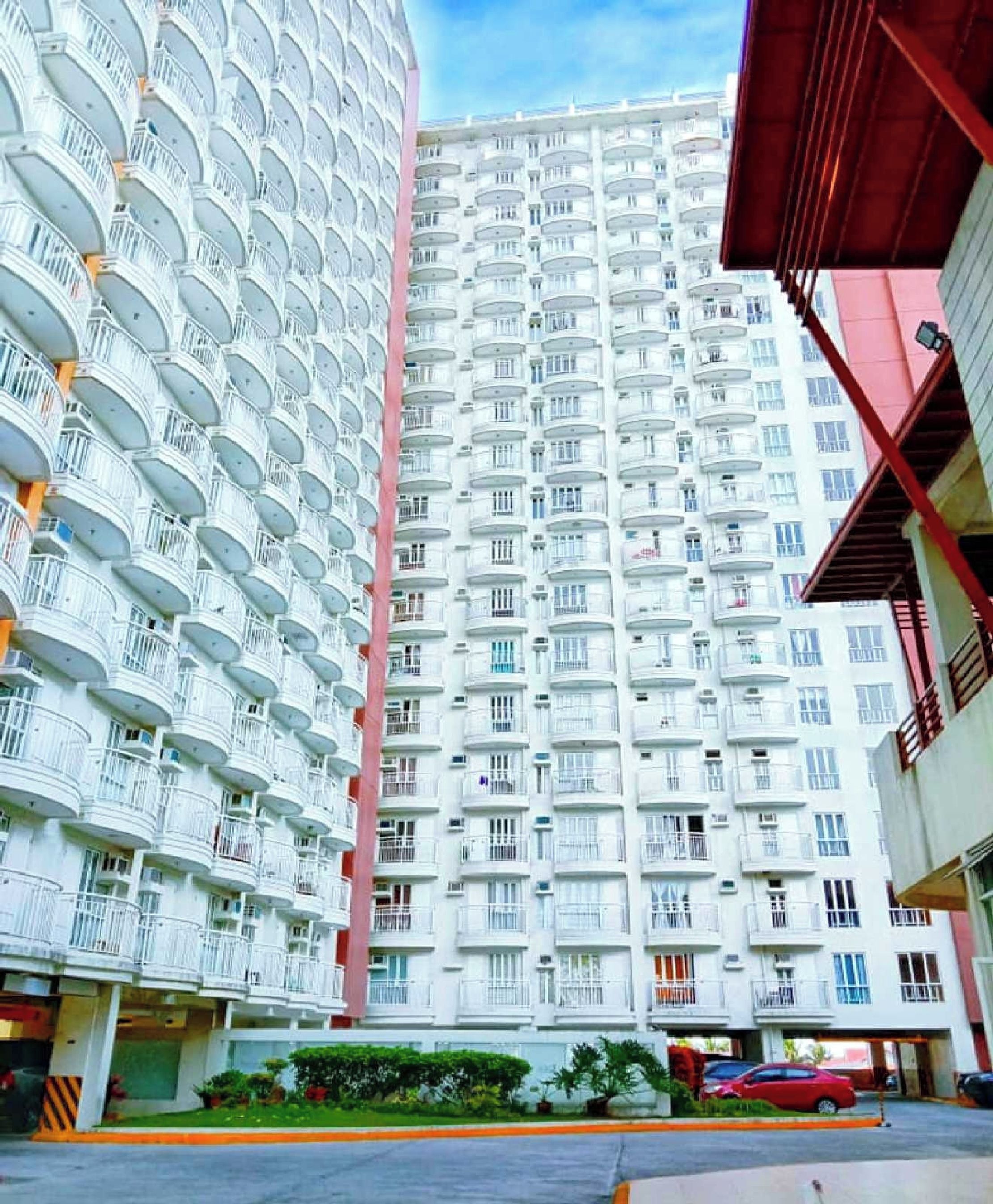 A multi-story residential building with balconies and a central vertical structure.