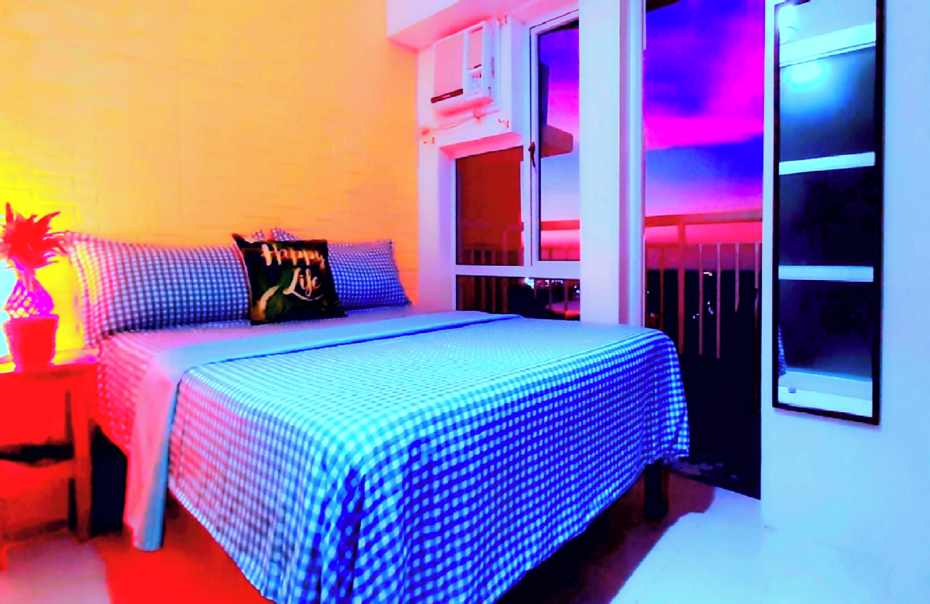 Un dormitorio con cama, almohadas, una mesita de noche y una ventana.