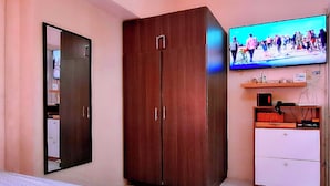 A bedroom with a wardrobe, a television mounted on the wall, and a small cabinet with drawers. - BestLove HideAway 1-BR *Parking, Pool (Tagaytay)