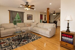 A living room with a sofa set, a coffee table, a patterned rug, a lamp, and a sideboard with folded blankets. - Cooperstown Baseball Rentals - Ballpark Holiday (Maryland)