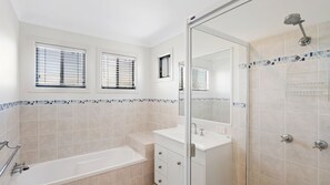 Un baño moderno con bañera, ducha y tocador con espejo.