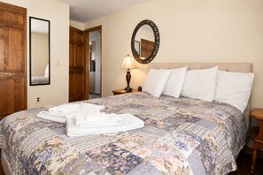 Ein Hotelzimmer mit einem großen Bett, einem Holzschrank, einem Spiegel und einer Lampe.