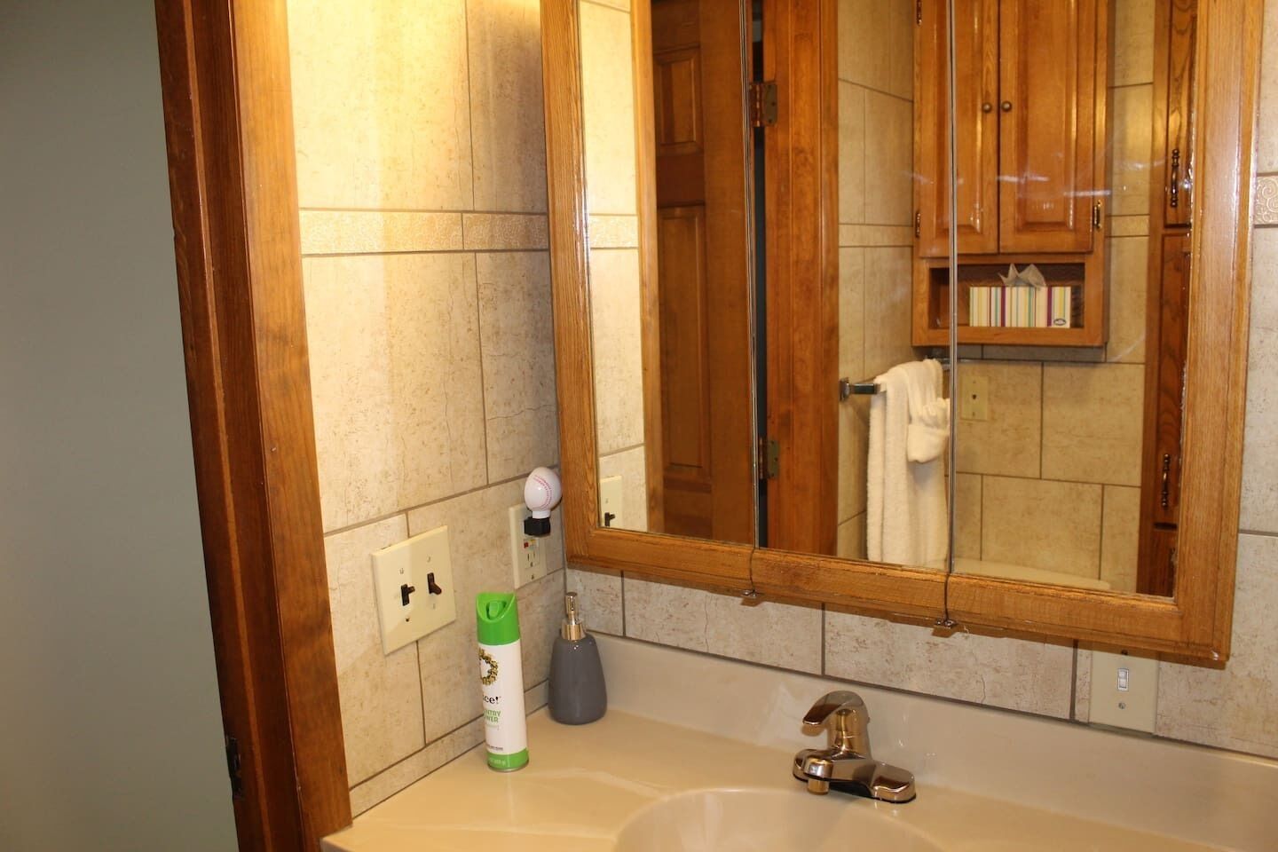 Un baño con tocador de madera, un espejo grande, un lavamanos y un perchero para toallas.