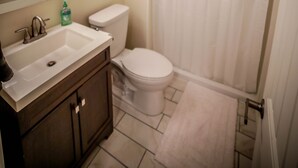 Une salle de bain équipée d’un lavabo, d’un miroir, de toilettes et d’un rideau de douche.