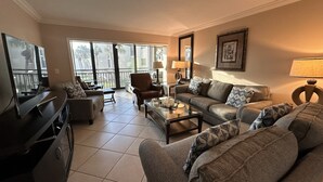 A living room with a sofa, armchair, coffee table, TV, and a balcony with a view. - Little slice of paradise, Siesta Dunes 2-209. (Siesta Key)