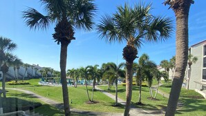 A well-maintained courtyard with palm trees, a pool area, and a building with a modern architectural style. - Little slice of paradise, Siesta Dunes 2-209. (Siesta Key)