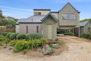 A two-story house with a covered driveway and a small garden area.