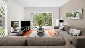 A modern living room with a sofa, a coffee table, and a TV. - Aireys Oasis (Aireys Inlet)