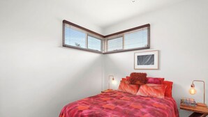 A bedroom with a bed, two bedside lamps, a framed picture on the wall, and a window with blinds. - Aireys Oasis (Aireys Inlet)