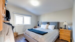 Een slaapkamer met een groot bed, een nachtkastje, een lamp en een kledingkast.