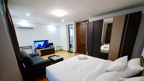 Ein Hotelzimmer mit einem Bett, einer Couch, einem Fernseher und einer Tür.