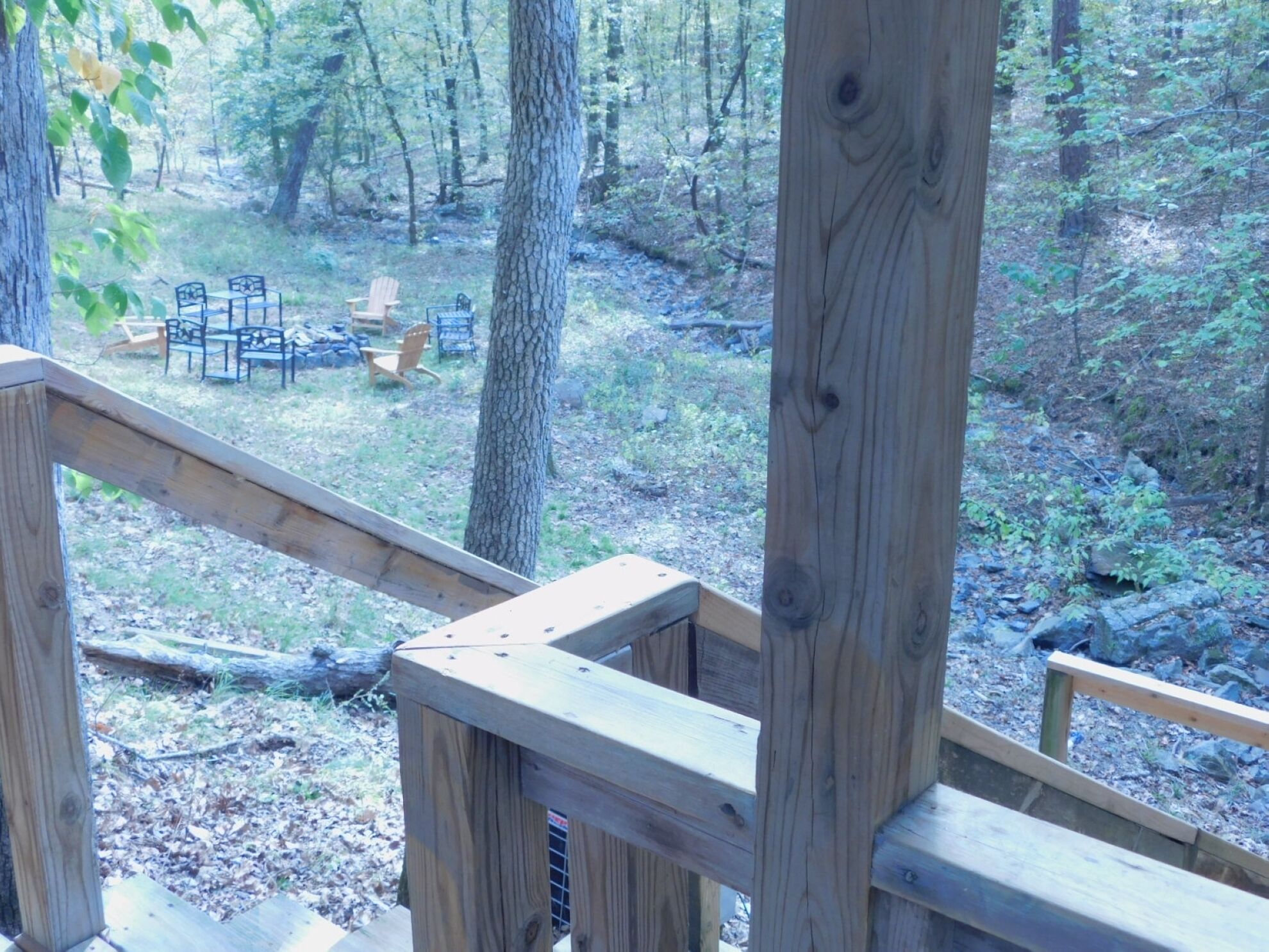 A wooden deck with a view of a forested area and outdoor furniture.