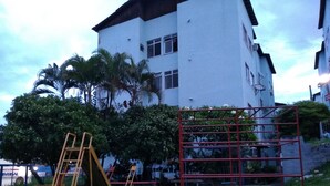 A playground with a yellow ladder and a red climbing frame in front of a white building with multiple windows and a balcony. - Apartment on Estrada do Pré in Campo Grande (Sen. Vasconcelos)