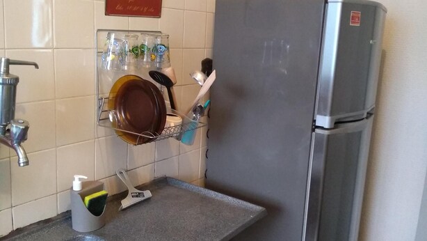 A kitchen with a stainless steel refrigerator, a sink with a purple towel, and a coffee-themed poster on the wall. - Apartment on Estrada do Pré in Campo Grande (Sen. Vasconcelos)