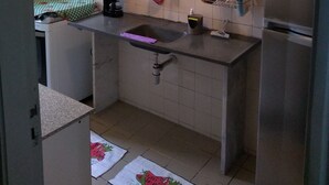 A kitchen with white tiled walls, a stainless steel refrigerator, a coffee machine, and a hanging pot rack. - Apartment on Estrada do Pré in Campo Grande (Sen. Vasconcelos)