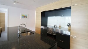 Una cucina moderna con piano di lavoro in granito nero, elettrodomestici in acciaio inossidabile e mobili in legno.