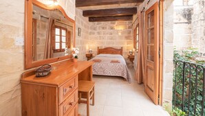 Ein Schlafzimmer mit einem Holzkasten, einem Bett mit gemustertem Überwurf und einer Steinsäule.