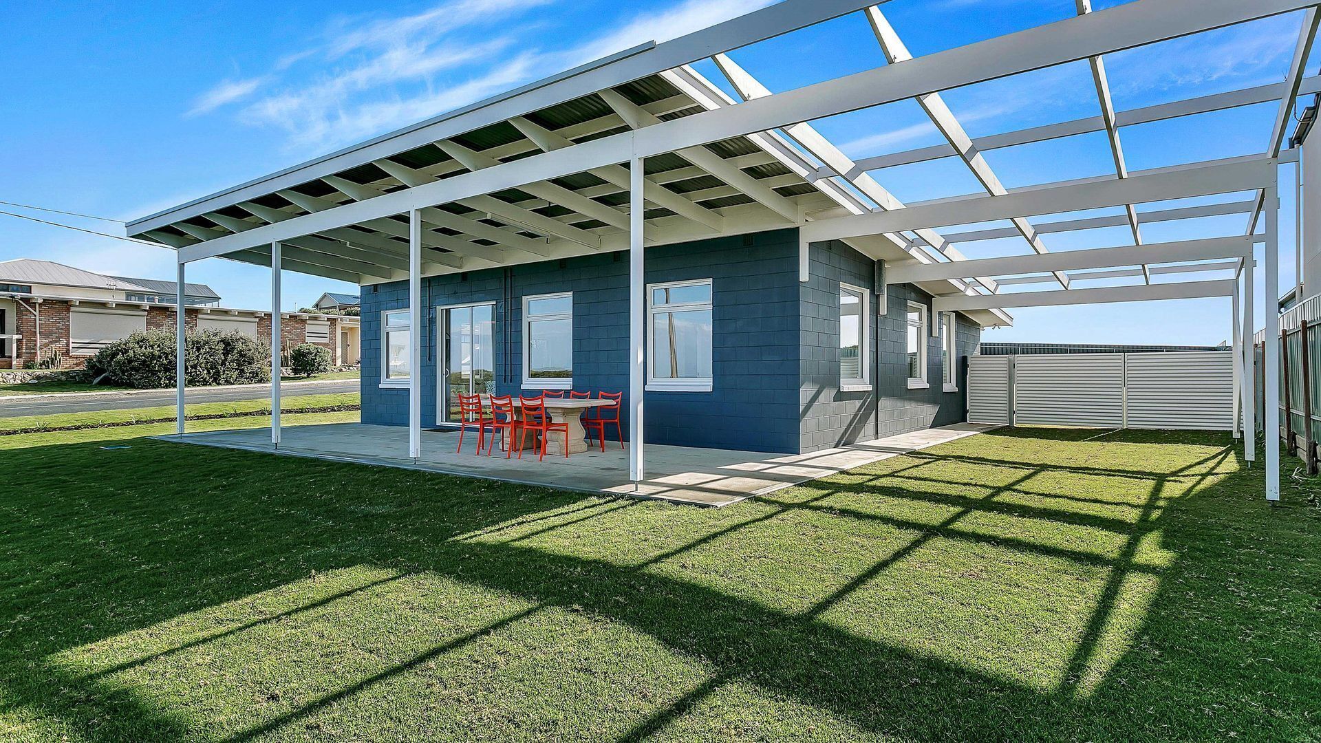 Une maison moderne dotée d’un patio couvert, d’une pelouse et d’un garage.