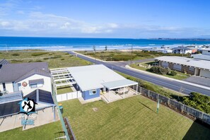 A coastal property with a large open patio, a covered outdoor seating area, and a view of the ocean.
