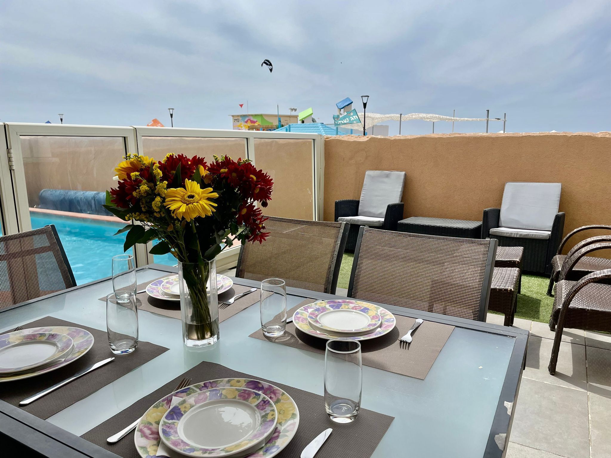 A table set for dining with a view of a pool and a clear sky.