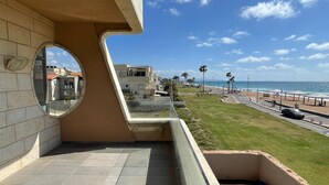 Un balcon avec vue sur une plage, une piscine et des immeubles d’habitation.