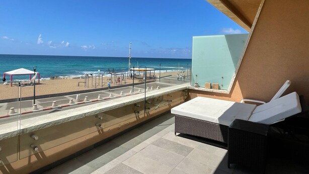 Un balcon avec vue sur la plage, du matériel d’exercice et un espace de détente avec une table et des chaises.