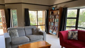 Un salon avec un canapé gris, un canapé rouge, une table basse en bois et une bibliothèque remplie de livres.