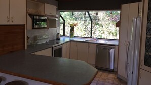 Une cuisine dotée d’un plan de travail en bois, d’appareils électroménagers en acier inoxydable et d’une fenêtre donnant sur un paysage verdoyant.