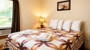 A hotel room with a bed, a lamp, a painting, and a window with curtains. - Cooperstown Baseball Rentals - Dugout 2 (Oneonta)