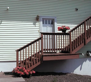 Stairs lead to a welcoming entrance with a small porch and a flower pot.