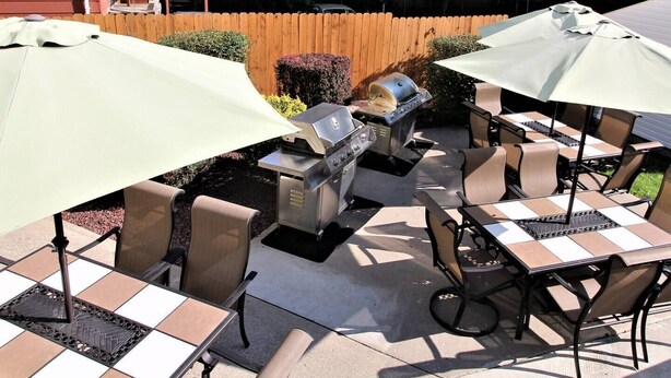 Une terrasse extérieure équipée d’un barbecue, de tables et de chaises.