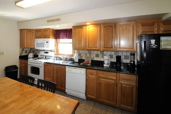 Kitchen area with a stove, refrigerator, and dining table.