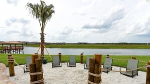 A beach area with lounge chairs and a palm tree, overlooking a body of water. - Private Pool & Lazy River! Storey Lake 4BR Home (kissimmee)