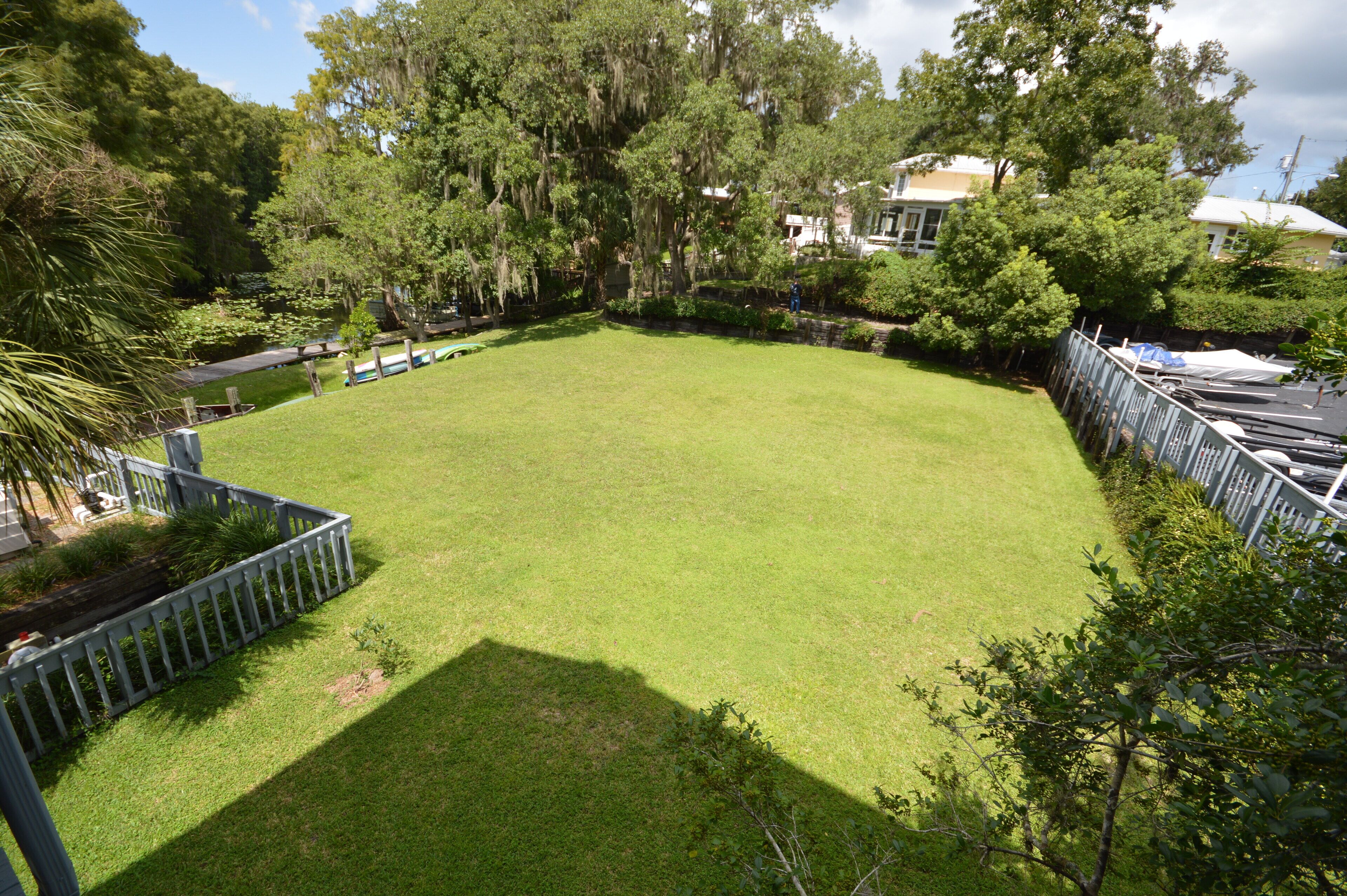 A well-maintained grassy area surrounded by trees and a white fence.