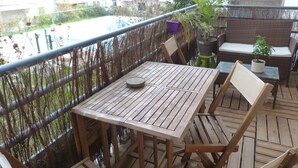 A wooden deck with a table and chairs, a wicker sofa, and potted plants. - The Chateaubriand Gerland (Lyon)