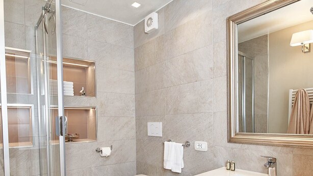 Un baño moderno con cabina de ducha de vidrio, lavamanos doble y un espejo grande.